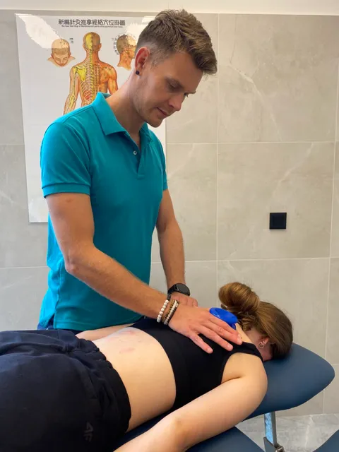 Paweł Grajewski wykonuje bańki na plecach pacjenta w gabinecie GraMedica